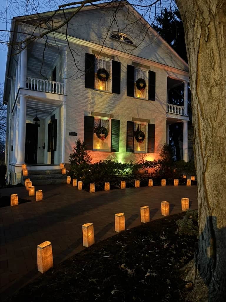 The house at dusk with warm luminaria lining the brick walk