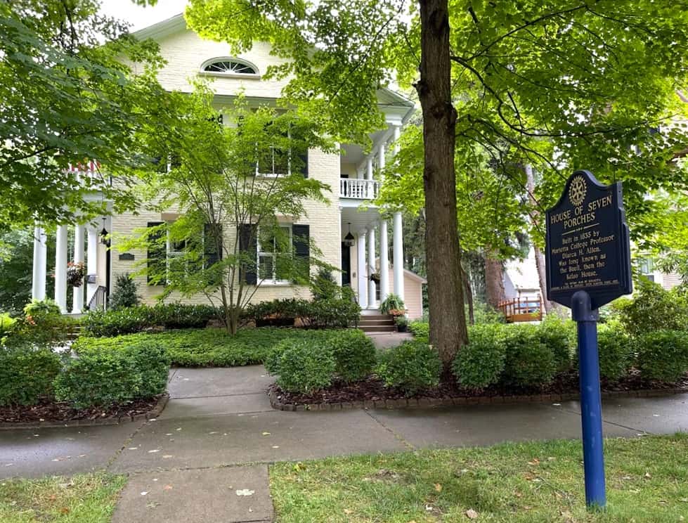 The house and its blue historical marker seen through summer trees